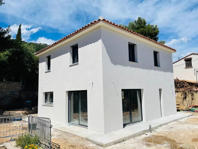 Maison individuelle à étage, façade enduite blanche, toiture en tuiles et menuiseries noires