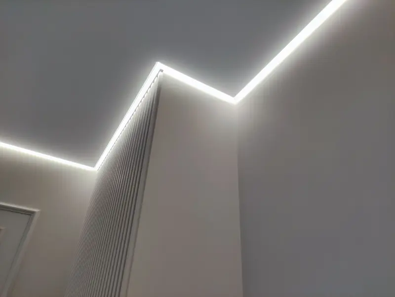 Ligne lumineuse LED en redents à la jonction entre plafond tendu et mur