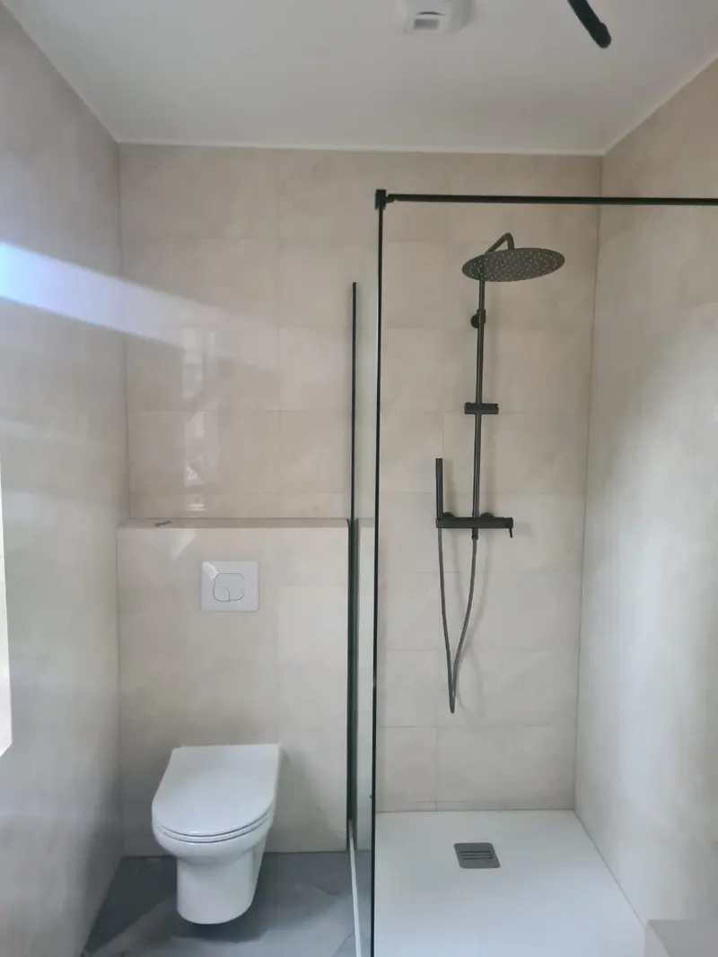 Salle d'eau avec douche à l'italienne, paroi vitrée à profil noir, colonne de douche noire et WC suspendu
